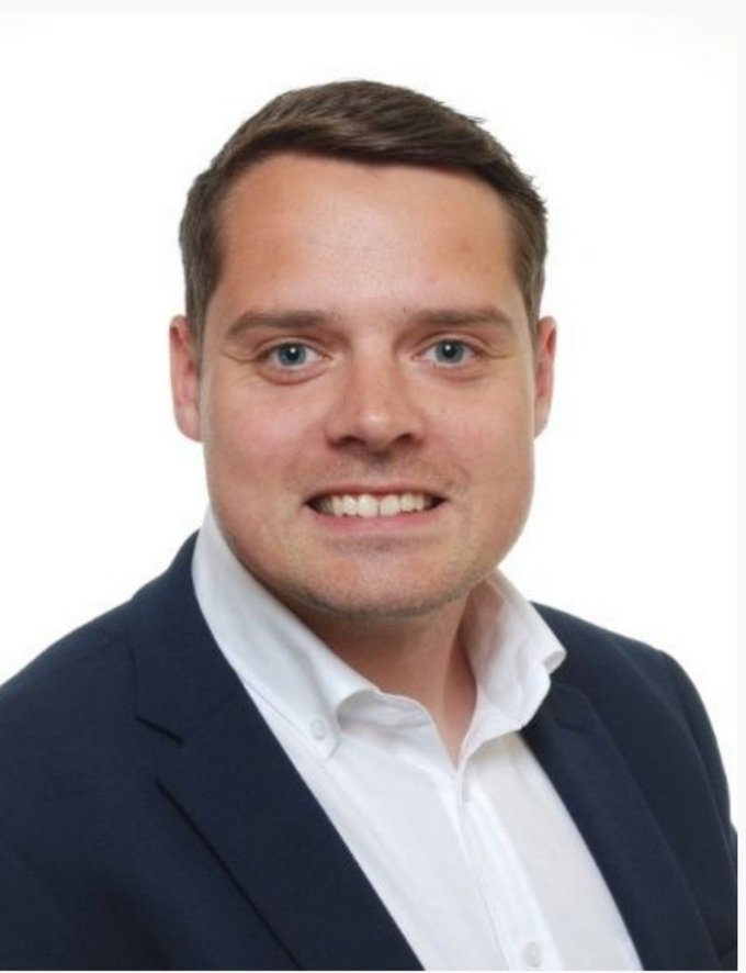 Tom Blumenstein, neuer Ausbildungsleiter der kubus IT, im Porträt Das Bild zeigt Tom Blumenstein, den neuen Ausbildungsleiter der kubus IT. Er trägt ein Hemd, lächelt freundlich in die Kamera und steht vor einem neutralen Hintergrund.